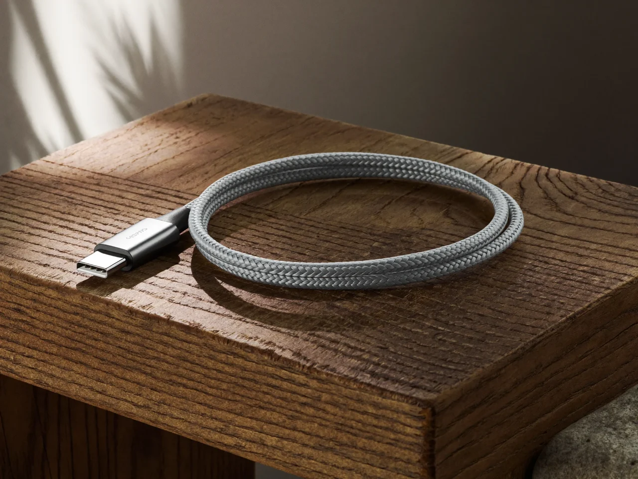 Geflochtenes USB-C-Kabel locker aufgerollt auf einem Eichenbrett