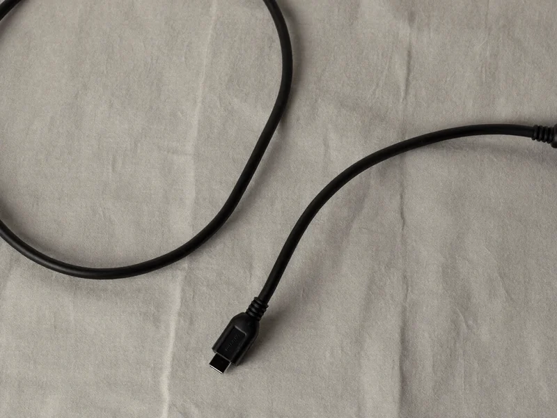 Zwei schwarze Videokabel in sanfter S-Kurve auf hellem Leinen