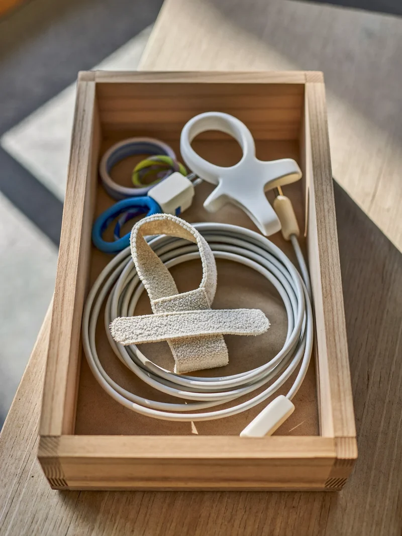 Holzkiste mit Kabelbindern, Clips und aufgerolltem Kabel auf Kraftpapier